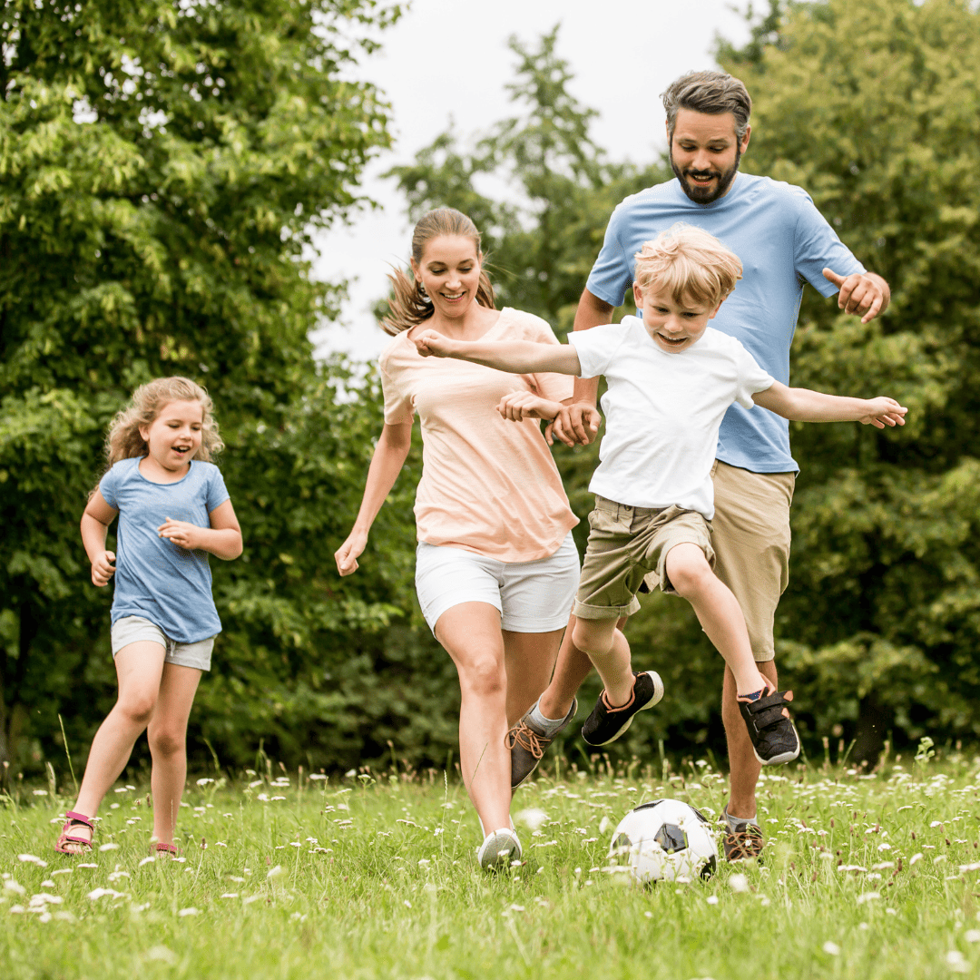 family playing soccer outside in field
