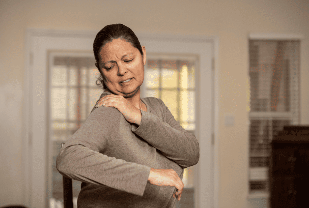 woman stretching and holding shoulder in discomfort