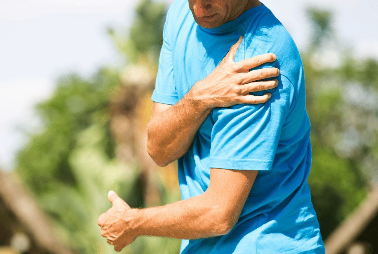 man outside holding shoulder in pain