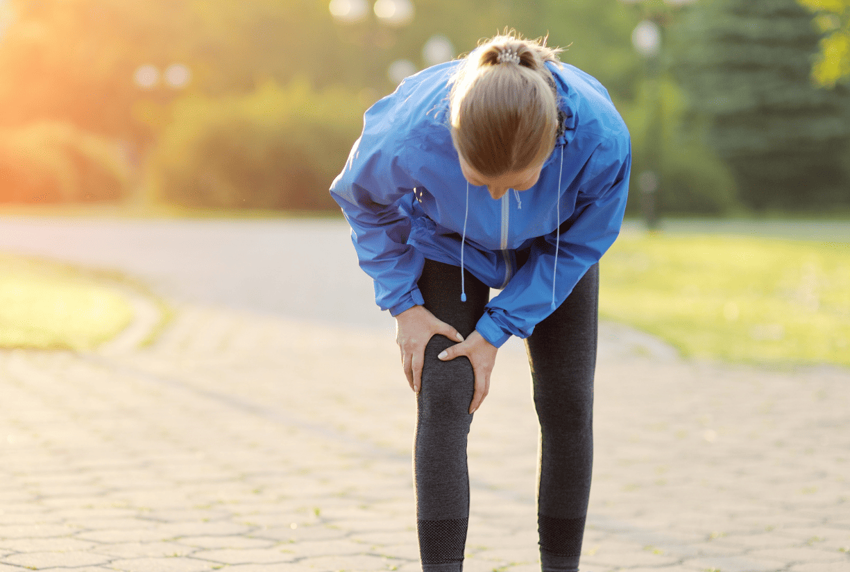 woman outside holding knee in pain