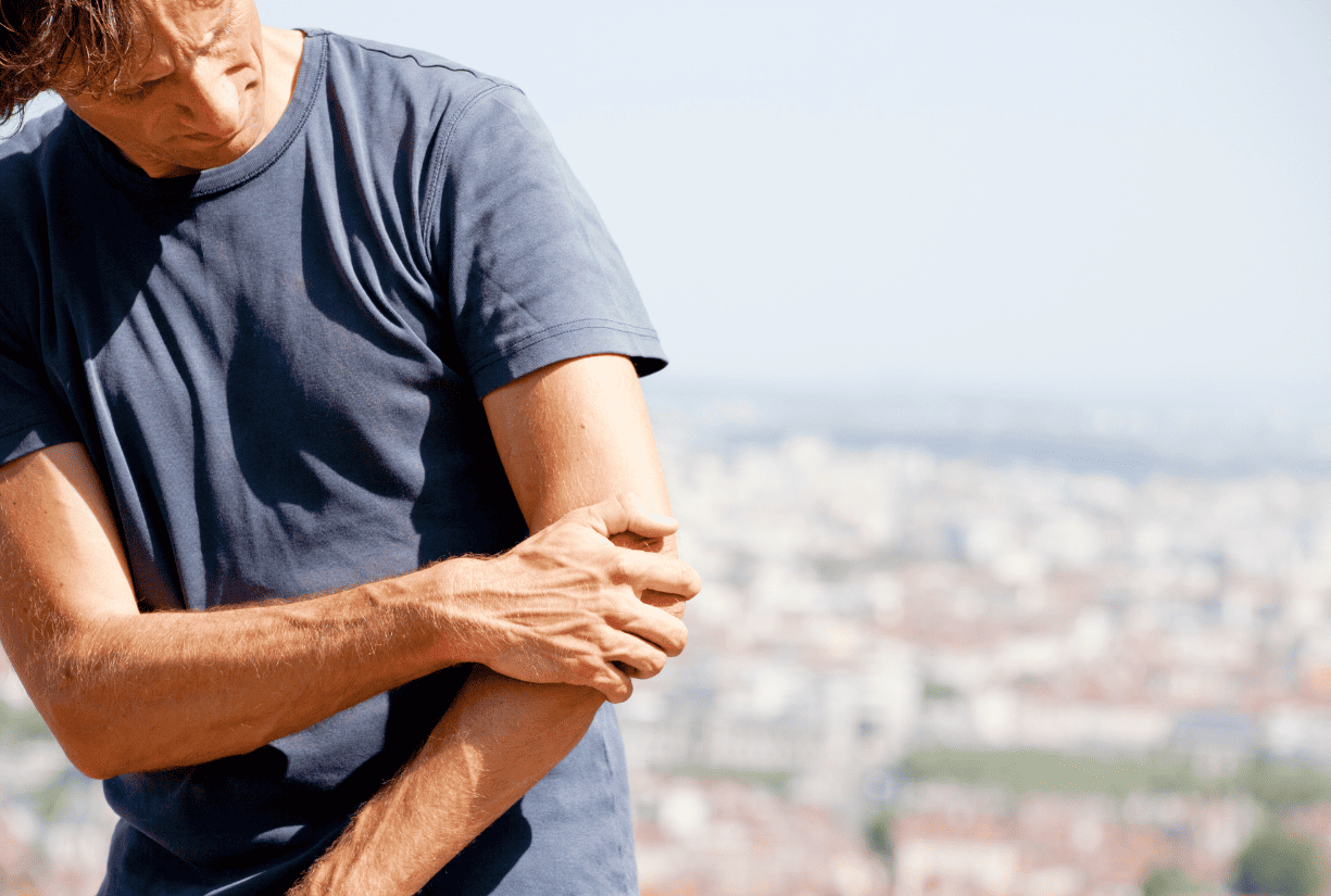 man outside holding elbow in pain