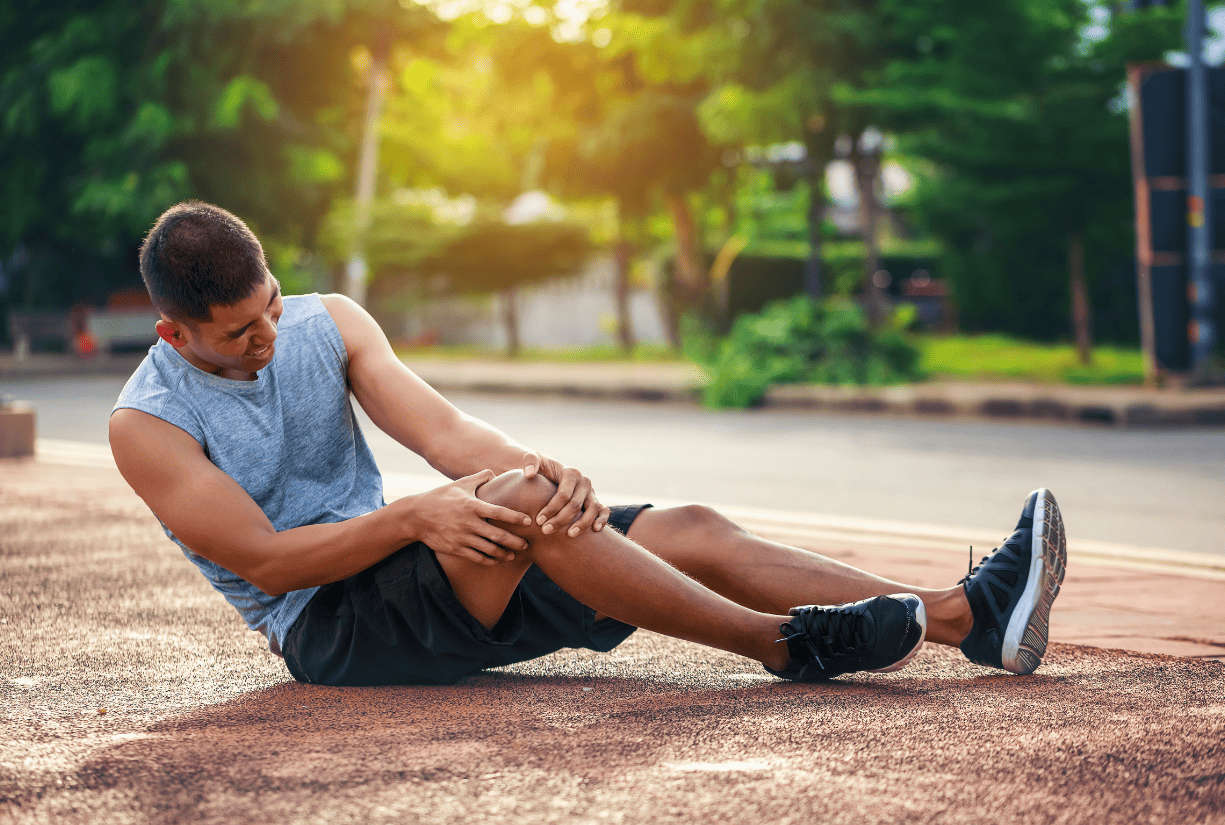 man in park holding knee in pain