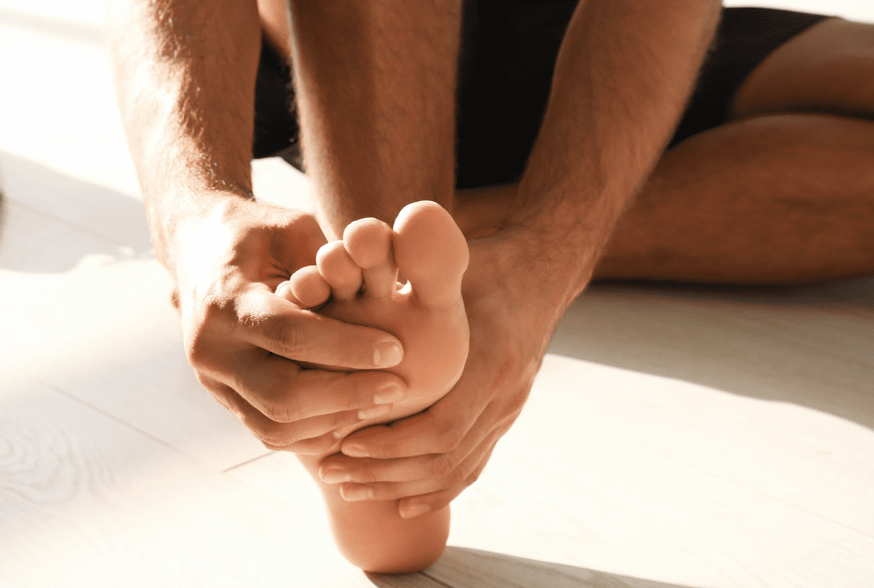 man in black shorts sitting down holding foot