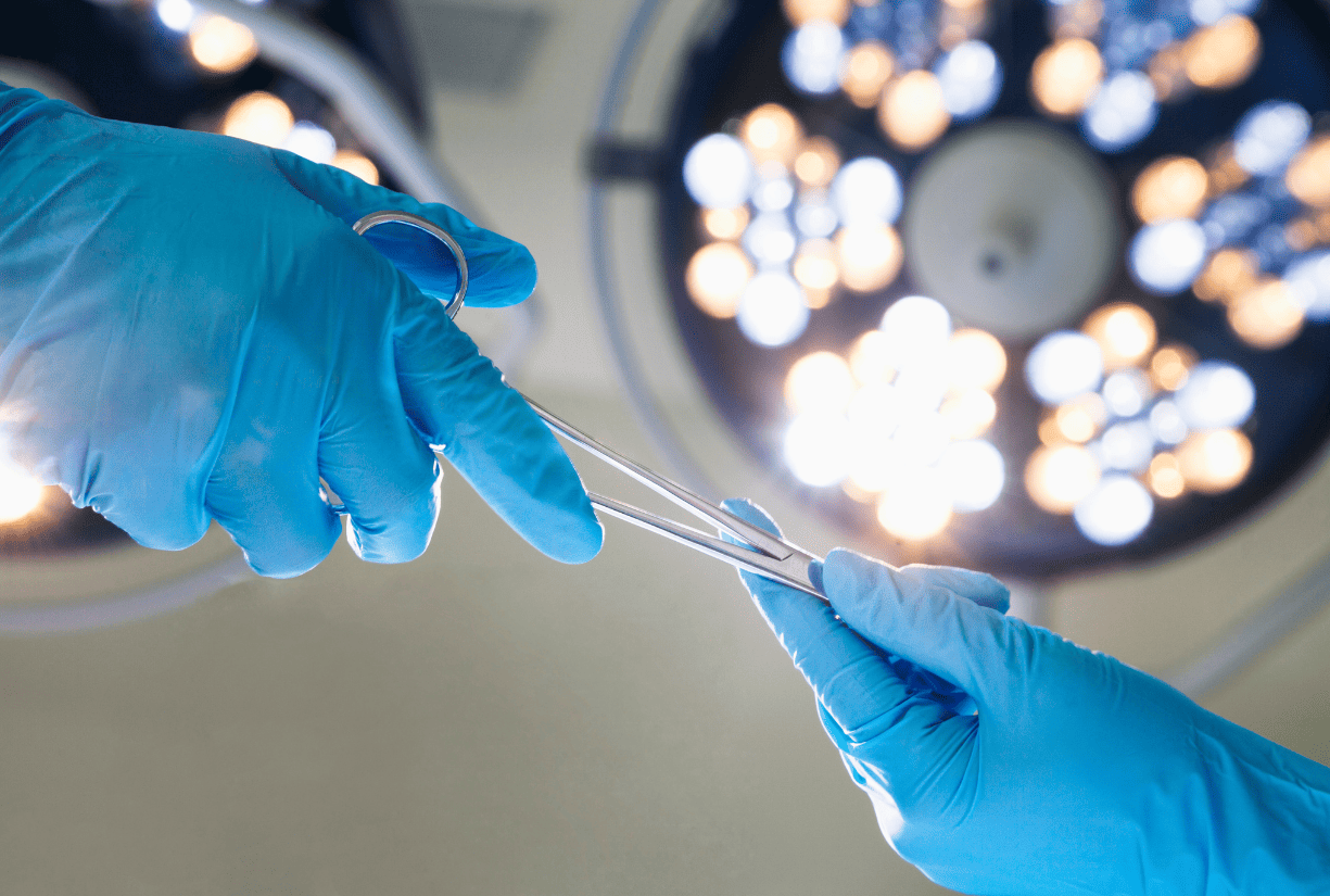 two hands wearing surgical gloves handing over surgical equipment