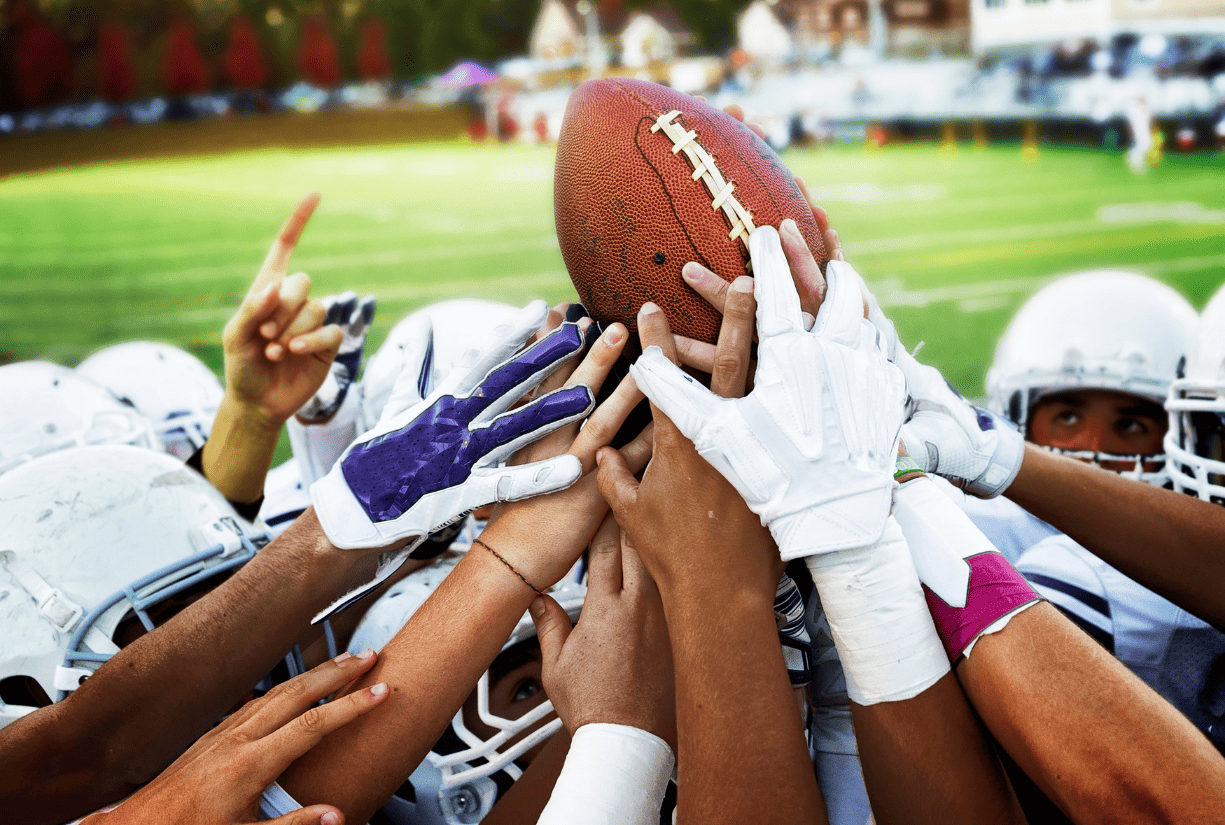 Football team group holding a football above the huddle