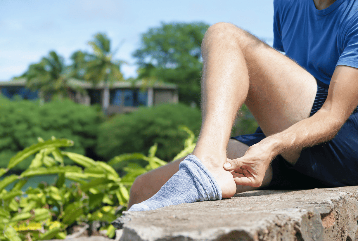 man sitting outside examining the back of his foot