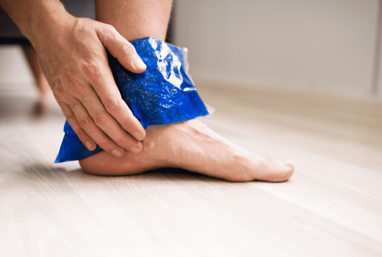 person holding icepack on ankle indoors