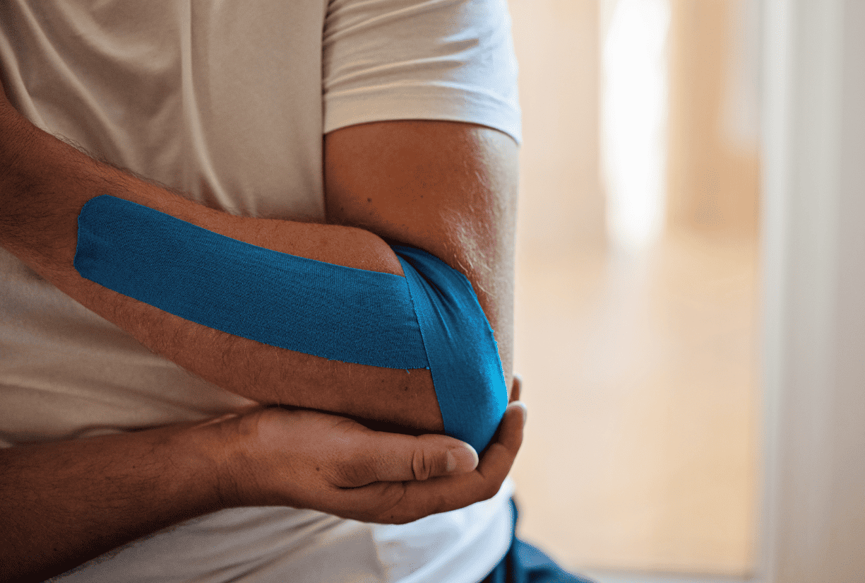 man holding up elbow wrapped in bandage